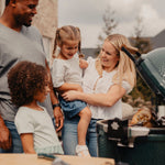 Family of four by a grill outdoors