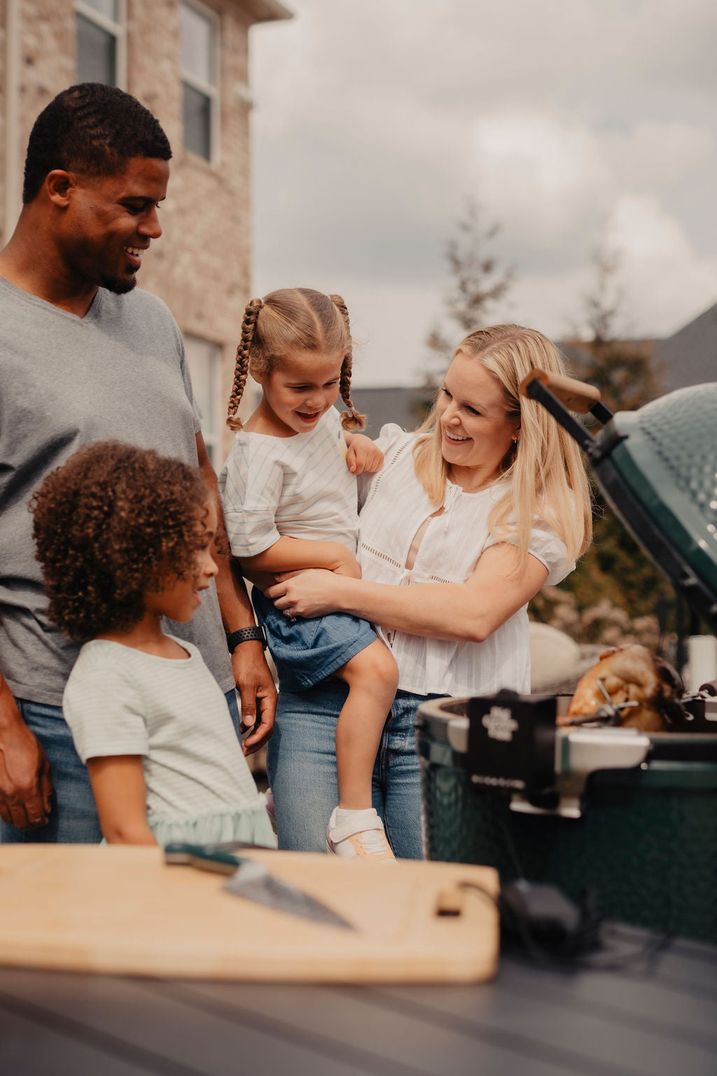 Family of four by a grill outdoors