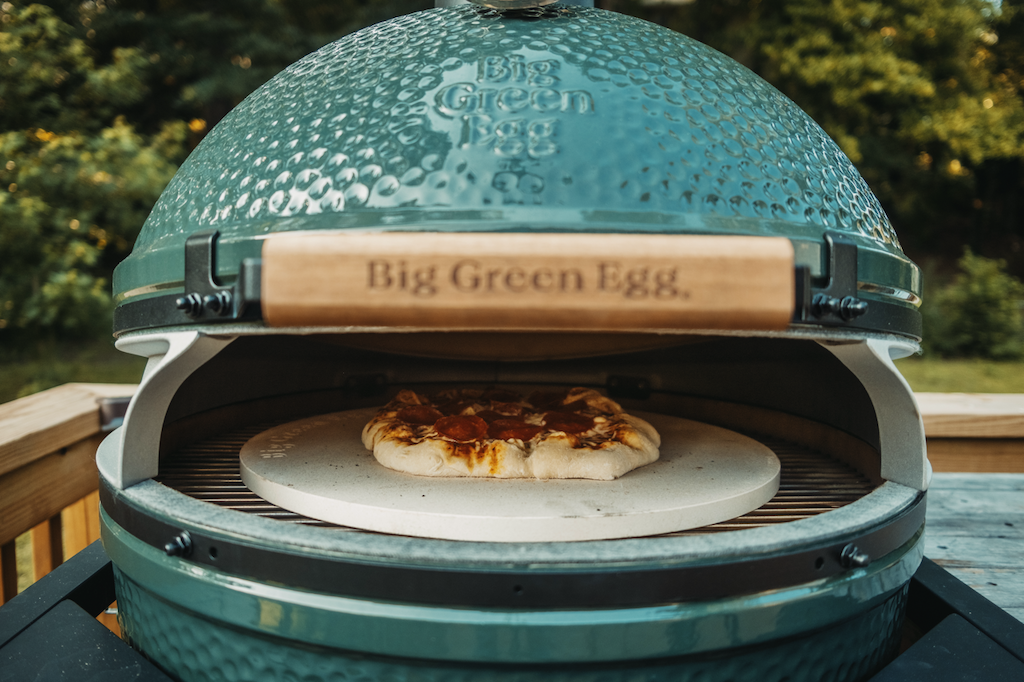 pizza on a baking stone on grill